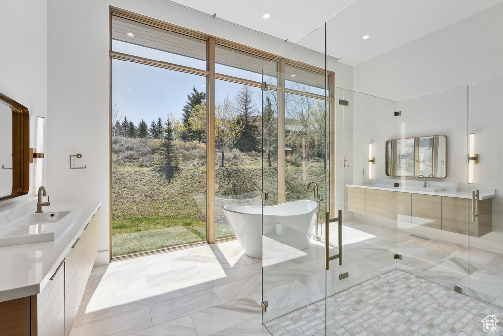 Full bathroom featuring vanity, a freestanding bath, a stall shower, recessed lighting, and a towering ceiling