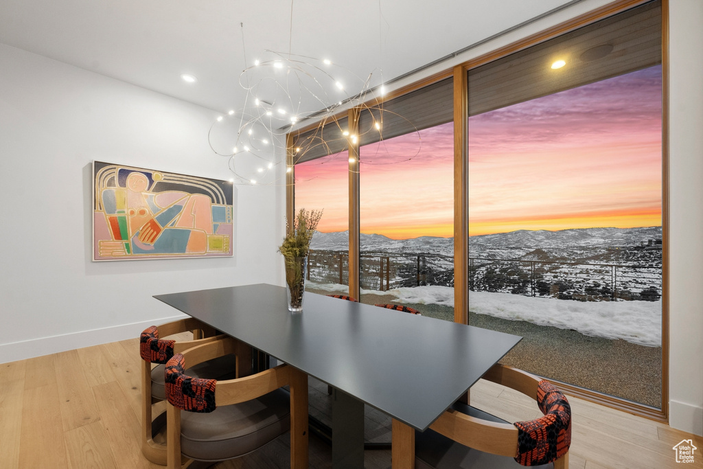 Dining area with a mountain view, light hardwood / wood-style floors, and a wall of windows