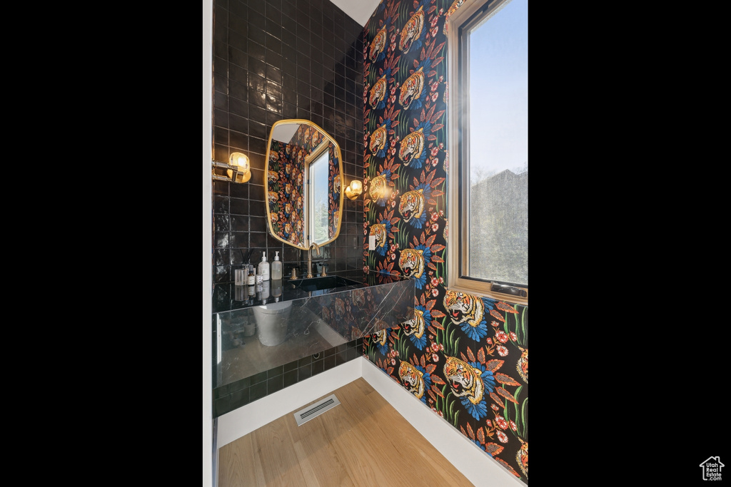 Bathroom with wallpapered walls, a sink, and wood finished floors