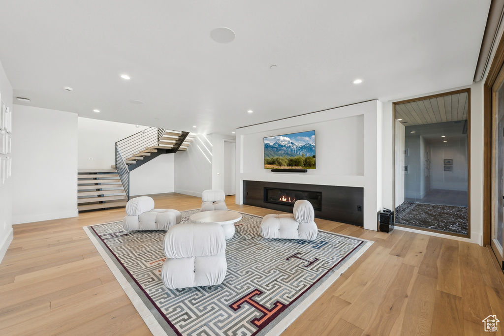 Living area featuring stairway, light wood-type flooring, a glass covered fireplace, recessed lighting, and baseboards