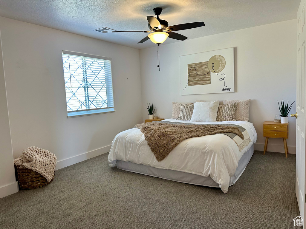 Carpeted bedroom featuring visible vents, baseboards, a ceiling fan, and a textured ceiling