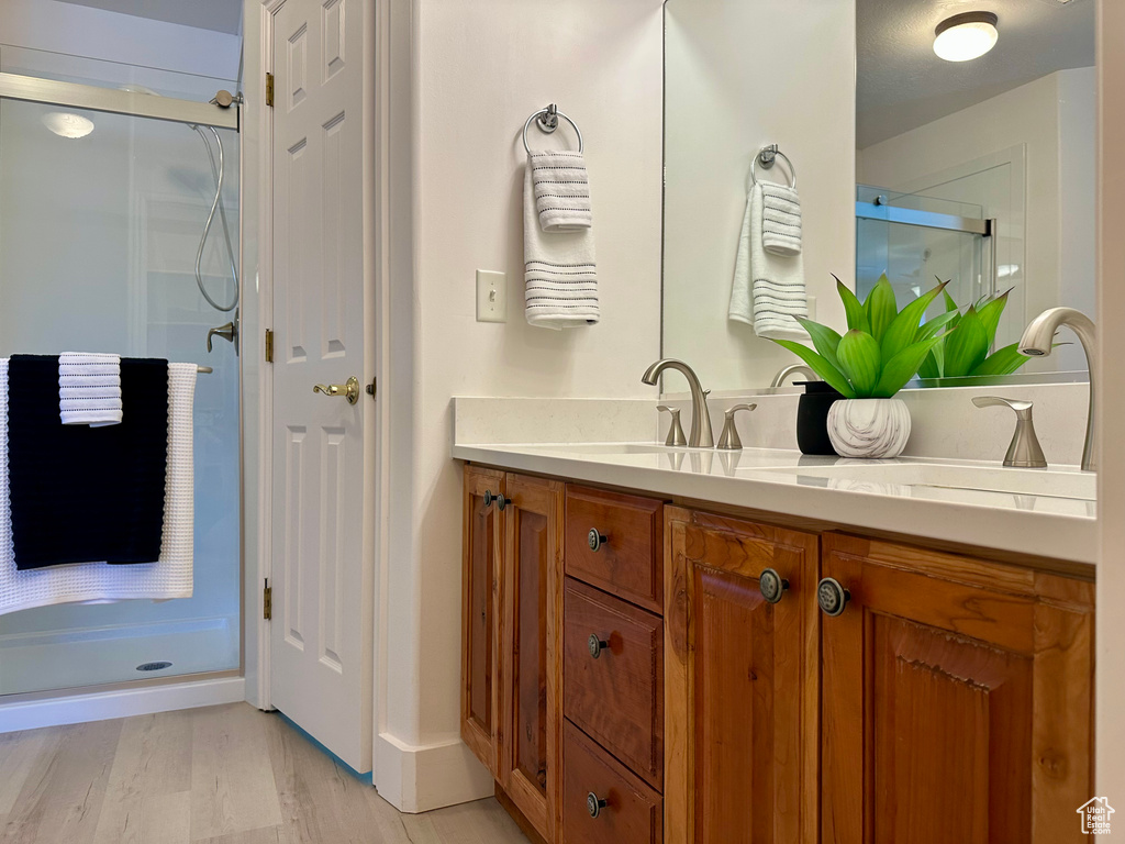Full bathroom featuring vanity, a stall shower, and wood finished floors