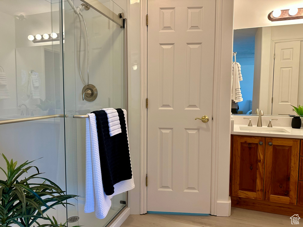 Full bath with vanity, a stall shower, and wood finished floors