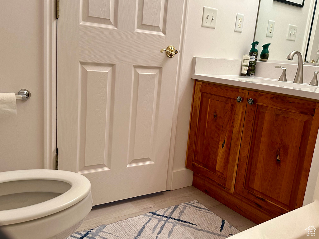 Bathroom featuring hardwood / wood-style flooring, vanity, and toilet