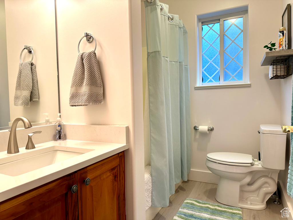 Bathroom featuring a shower with curtain, vanity, toilet, and wood-type flooring