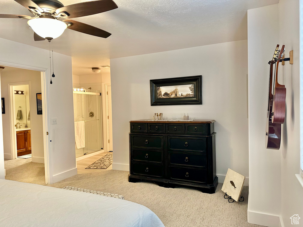 Bedroom with light carpet, ensuite bath, and ceiling fan