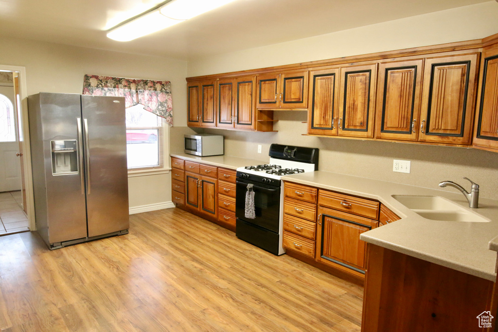 Kitchen featuring stainless steel appliances, sink, and light wood-type flooring