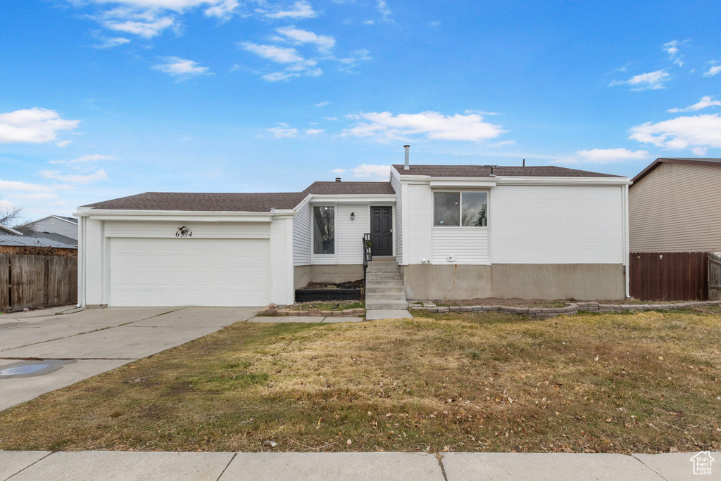 Single story home with a garage and a front lawn