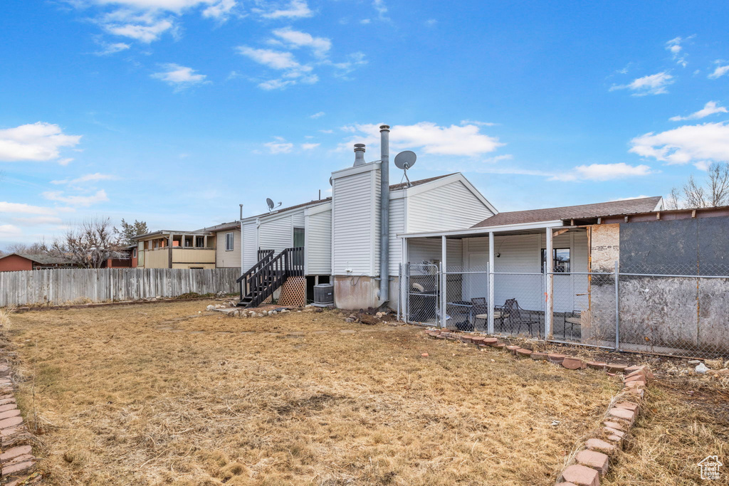 Rear view of house with a lawn and central air condition unit