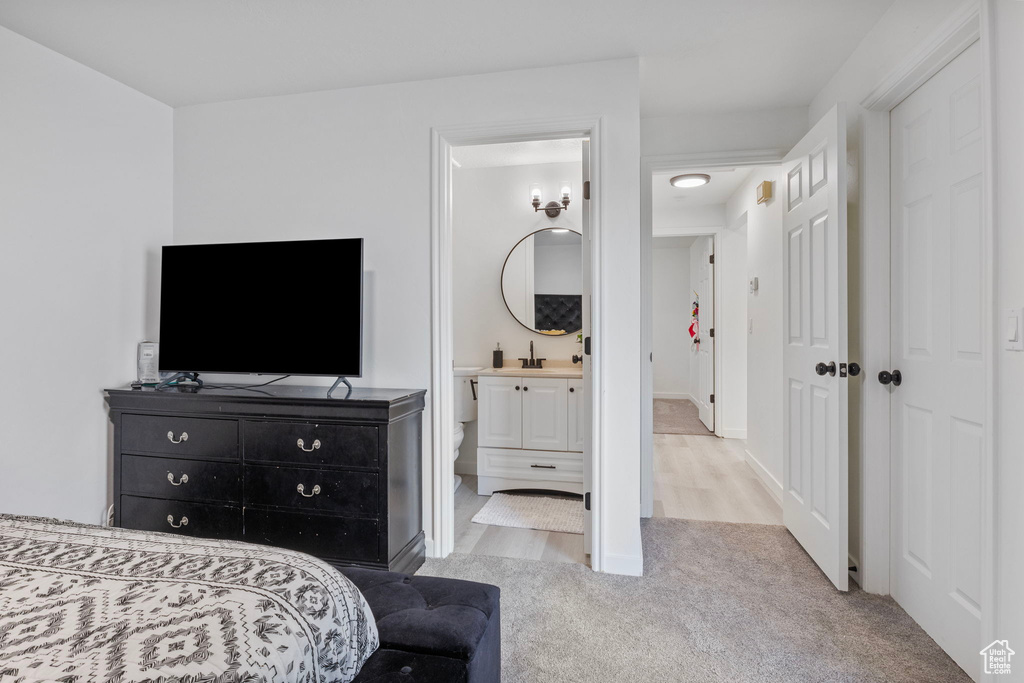 Bedroom with sink, light carpet, and ensuite bath