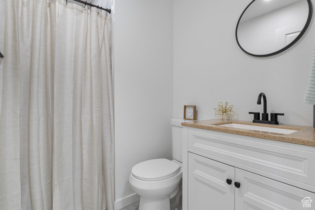 Bathroom featuring a shower with curtain, vanity, and toilet