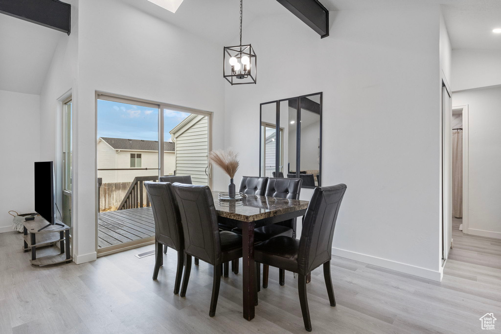 Dining area featuring high vaulted ceiling, beam ceiling, a chandelier, and light hardwood / wood-style floors