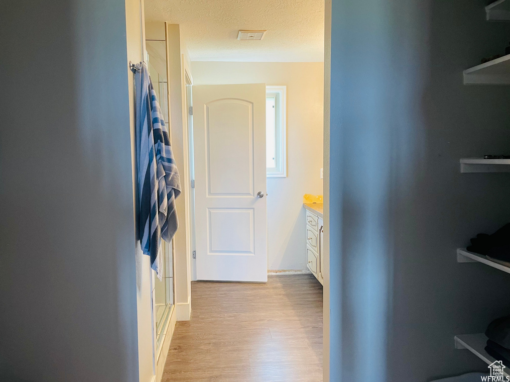 Hall featuring light hardwood / wood-style floors and a textured ceiling