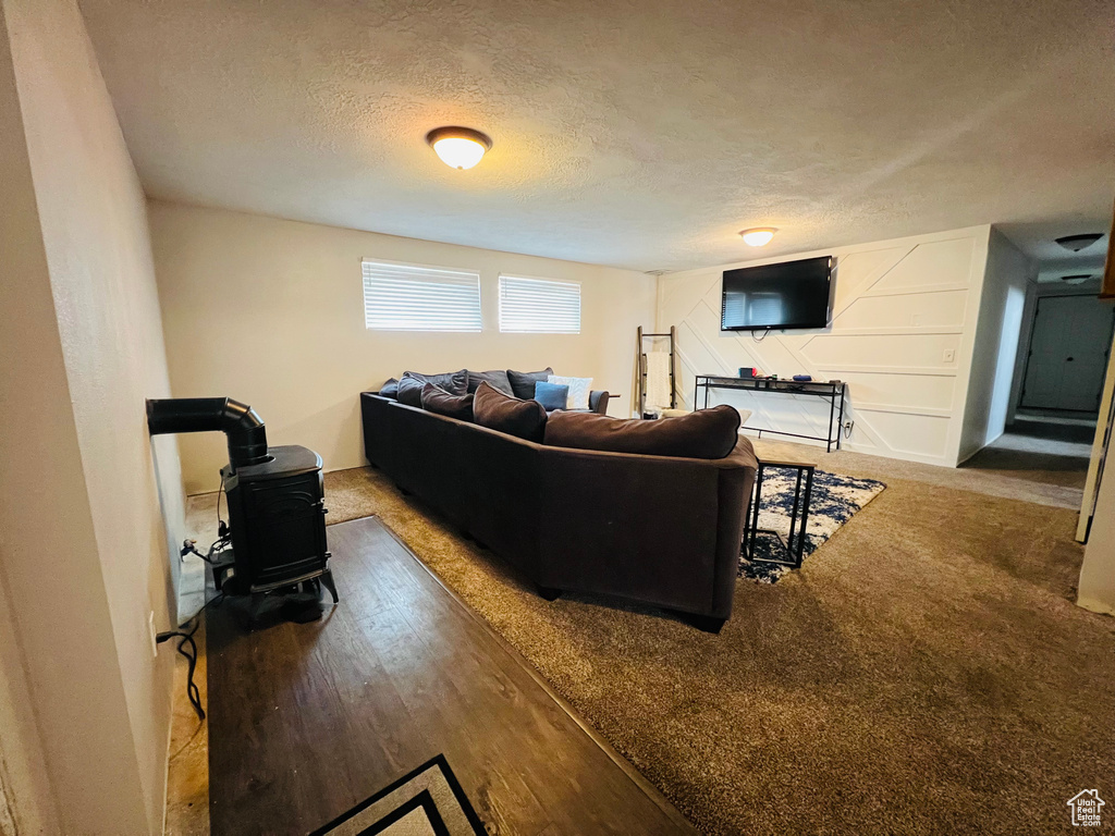 Living room featuring hardwood / wood-style flooring, a textured ceiling, and a wood stove