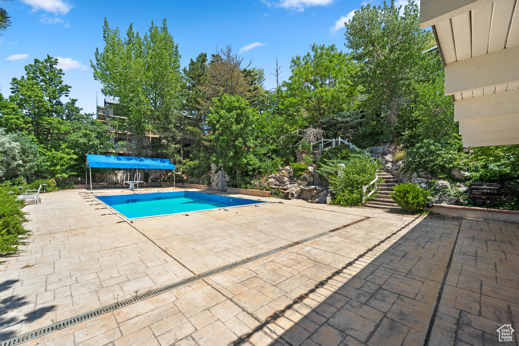 View of pool featuring a patio area, stairs, and a covered pool