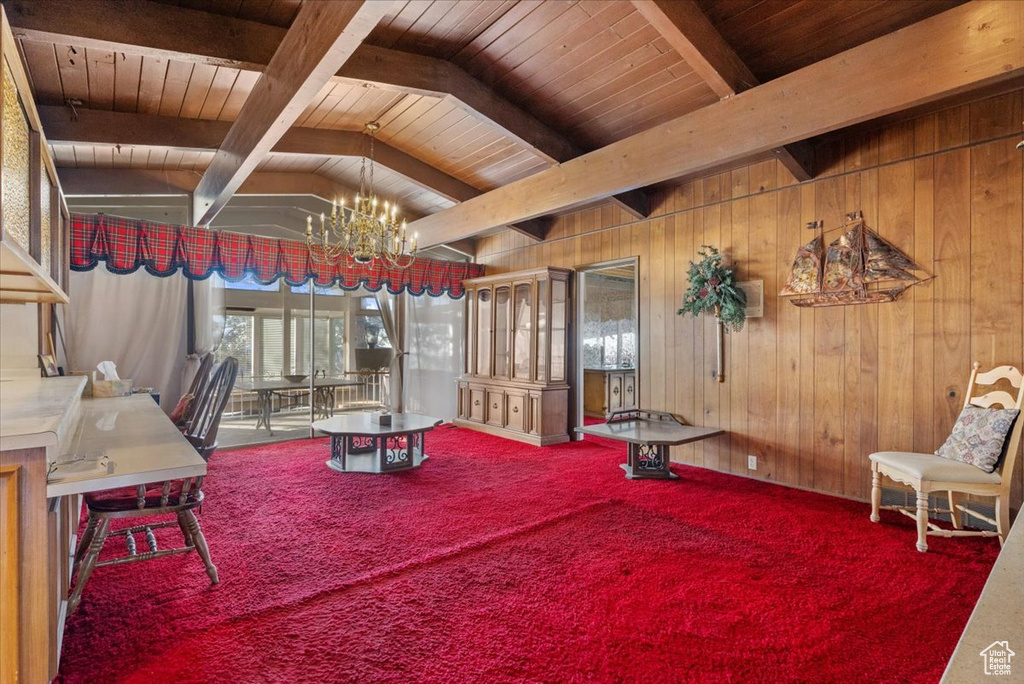 Interior space with lofted ceiling with beams, carpet floors, a chandelier, and wood walls