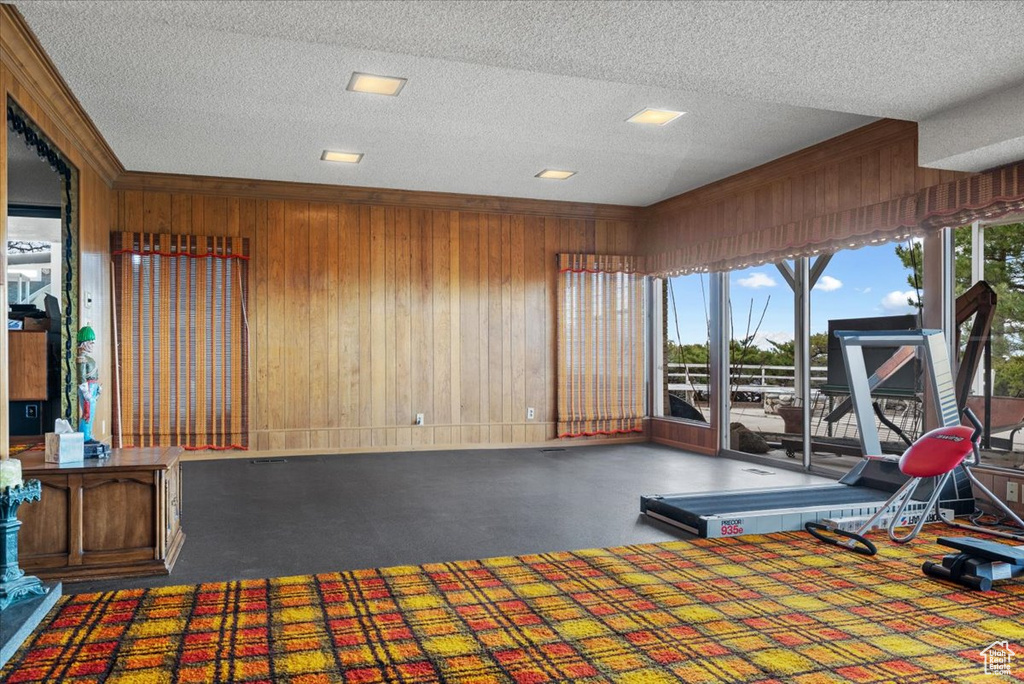 Exercise area featuring wooden walls and a textured ceiling
