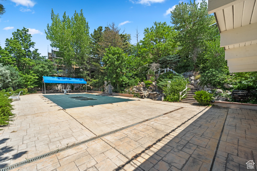 View of swimming pool with stairway, a patio, and a hot tub