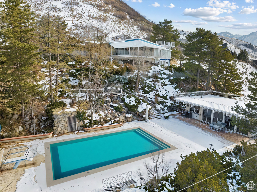 Snow covered pool with a mountain view and a patio area