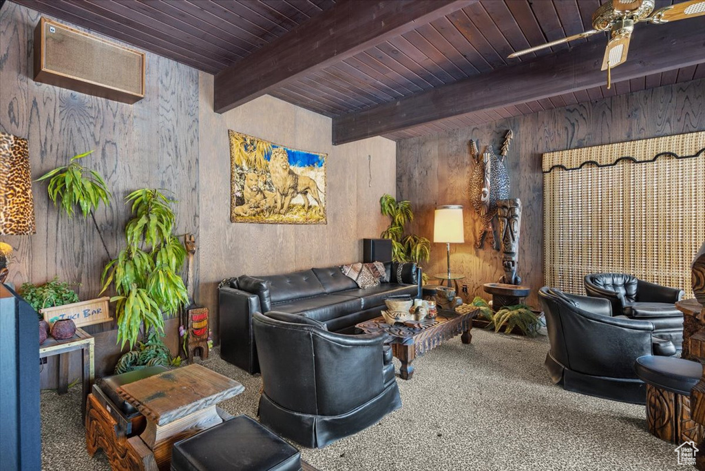 Carpeted living room with ceiling fan, wooden ceiling, beam ceiling, and wood walls