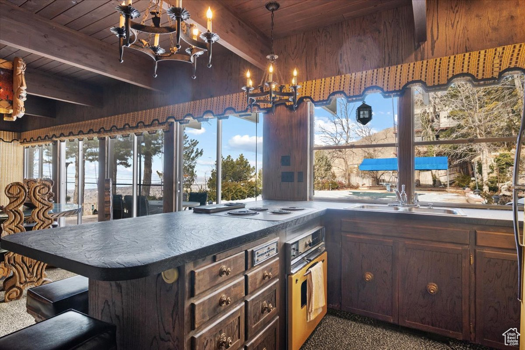 Kitchen featuring wall oven, decorative light fixtures, wooden ceiling, kitchen peninsula, and a chandelier