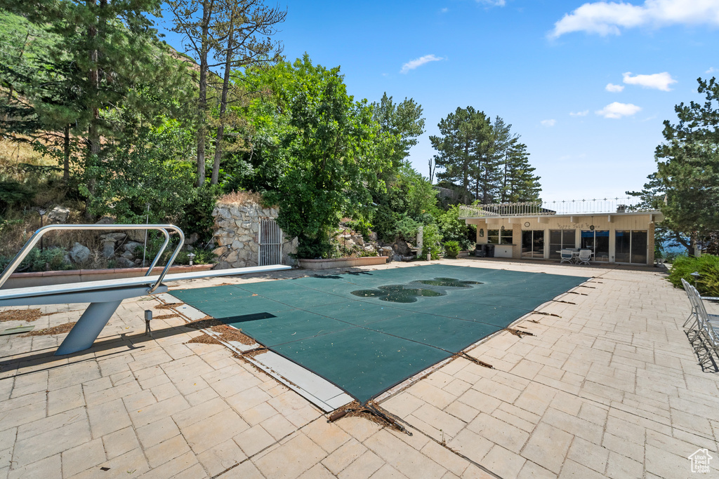 View of pool featuring a patio area, a diving board, and a covered pool