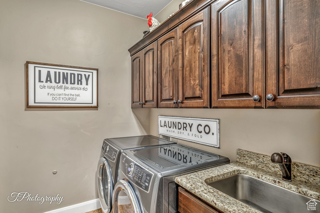 Laundry area featuring independent washer and dryer, sink, and cabinets