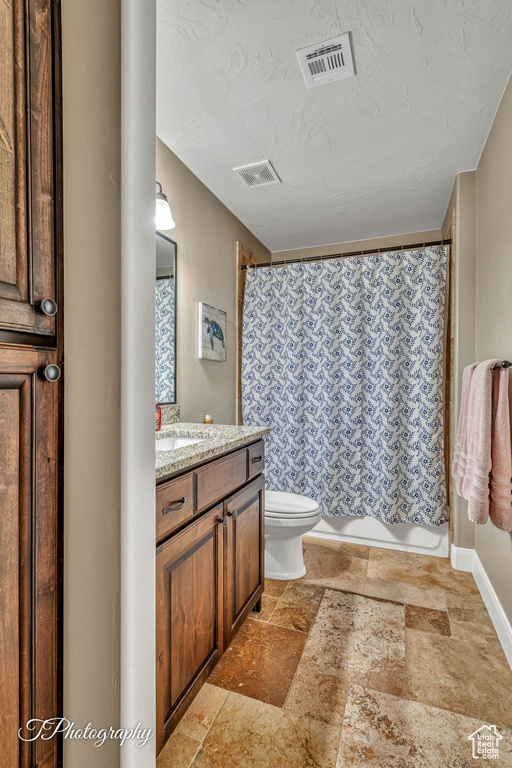 Bathroom featuring vanity, a shower with shower curtain, a textured ceiling, and toilet