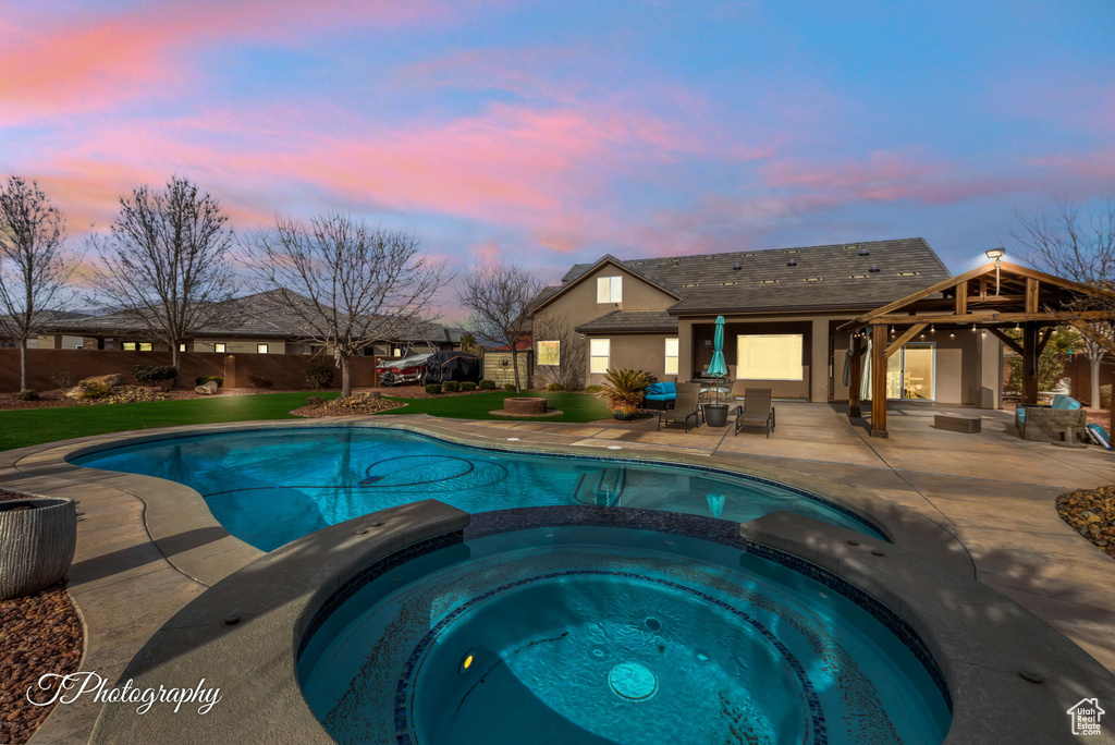 Pool at dusk featuring an in ground hot tub, a gazebo, and a patio area