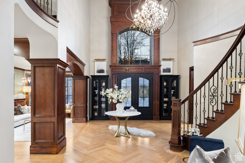Foyer featuring a towering ceiling, stairway, a chandelier, and decorative columns
