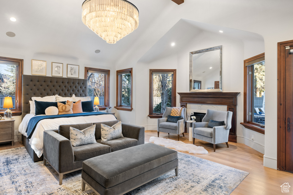 Bedroom with recessed lighting, light wood-type flooring, a chandelier, a high end fireplace, and vaulted ceiling