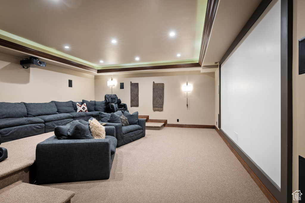 Carpeted home theater room with a tray ceiling, ornamental molding, and recessed lighting