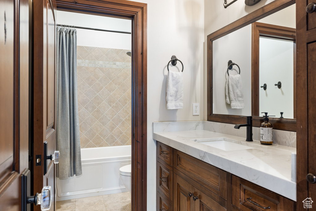 Bathroom featuring vanity, shower / bath combo with shower curtain, and tile patterned flooring