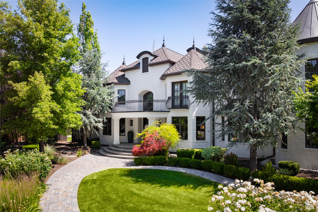 View of front facade featuring a balcony, stucco siding, and a front lawn