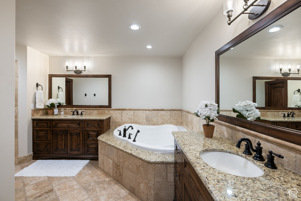 Bathroom featuring two vanities, a garden tub, and recessed lighting