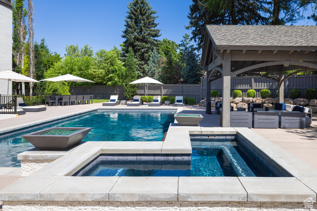 View of swimming pool featuring an in-ground hot tub, a fenced backyard, a patio area, and a gazebo