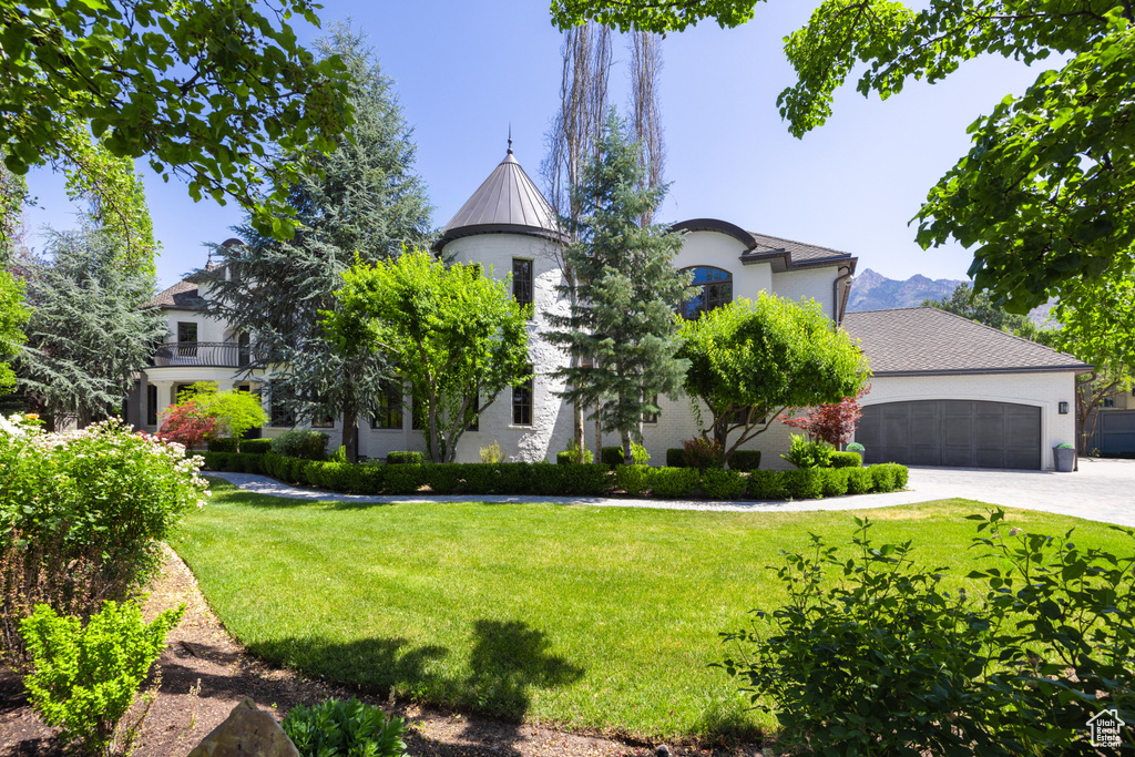 View of front of property with a front yard, driveway, an attached garage, stucco siding, and a standing seam roof