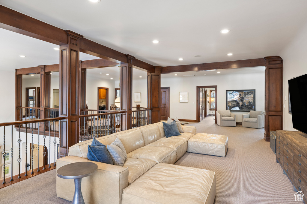 Living room with ornate columns, recessed lighting, and light carpet