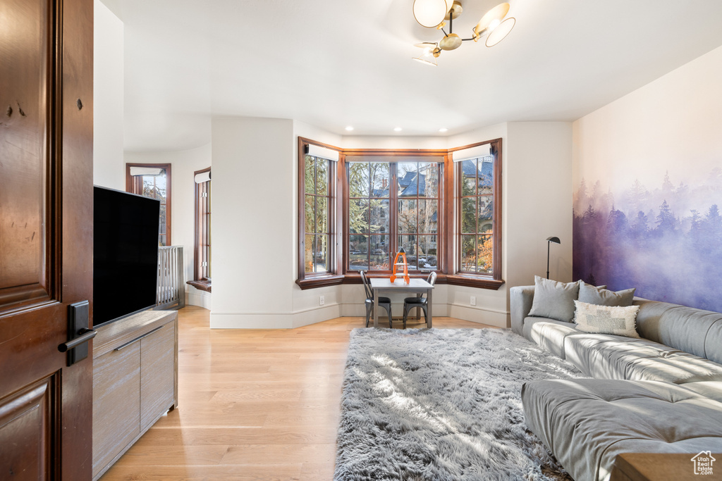 Living room with light wood-type flooring, a chandelier, and recessed lighting