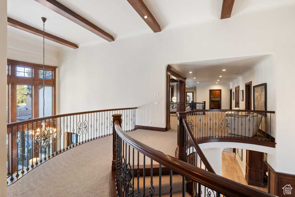 Hall with beam ceiling, an upstairs landing, carpet, a chandelier, and recessed lighting