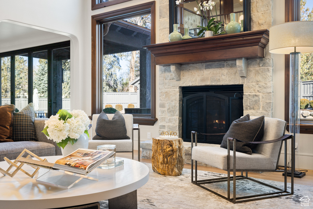 Living room featuring wood finished floors, plenty of natural light, a stone fireplace, and a chandelier