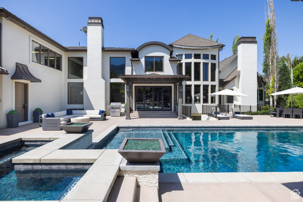 View of swimming pool featuring a patio, a grill, outdoor lounge area, and a pool with connected hot tub