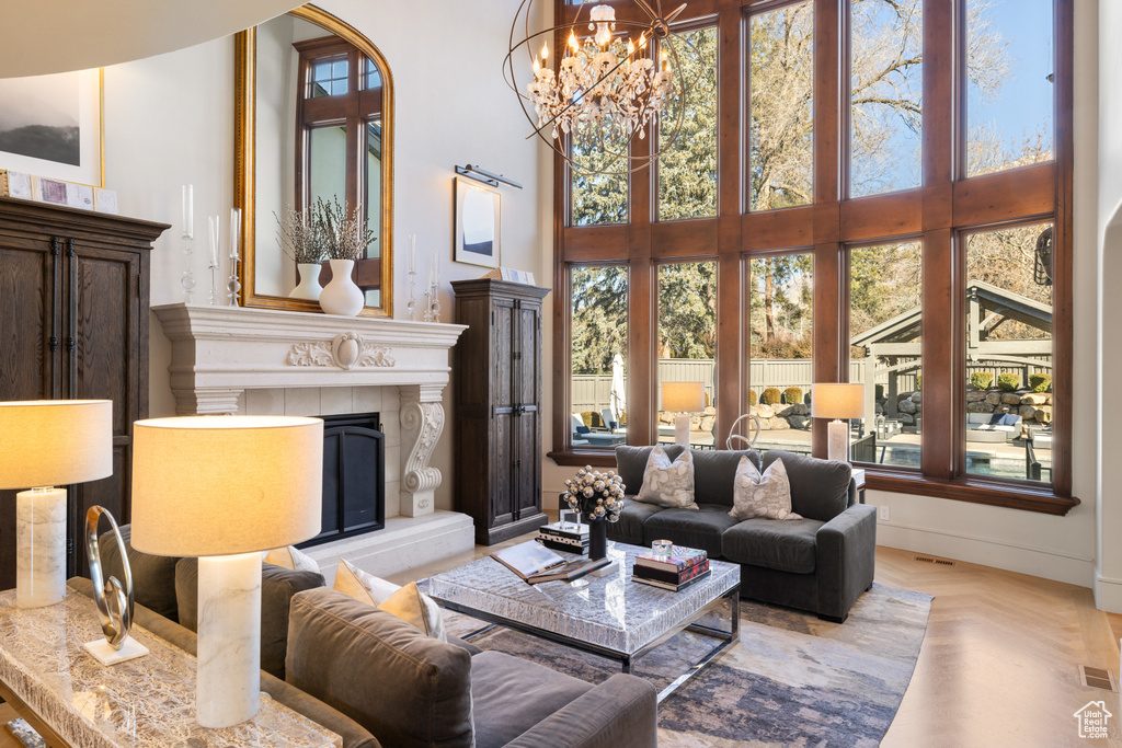 Living room with a high ceiling, a tile fireplace, and a chandelier