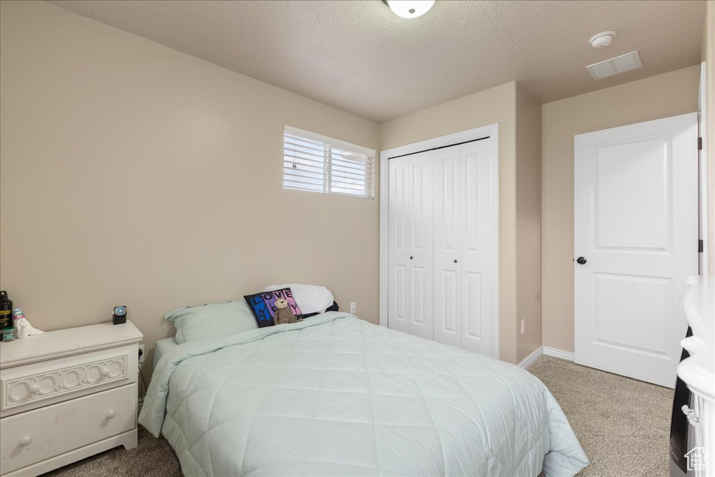 Carpeted bedroom featuring a closet and a textured ceiling