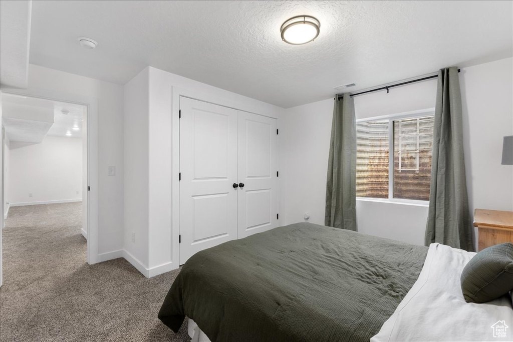 Bedroom featuring carpet floors, a closet, and a textured ceiling