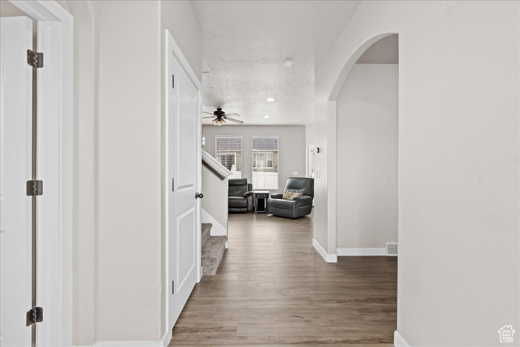 Hallway with hardwood / wood-style floors and a textured ceiling