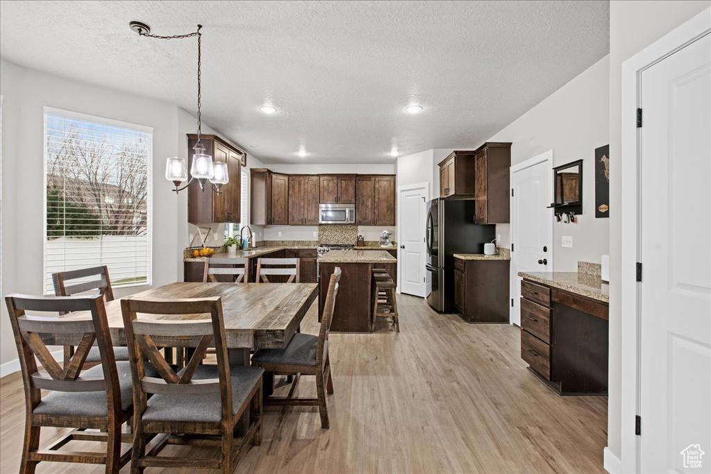 Dining space featuring sink, an inviting chandelier, a textured ceiling, and light wood-type flooring