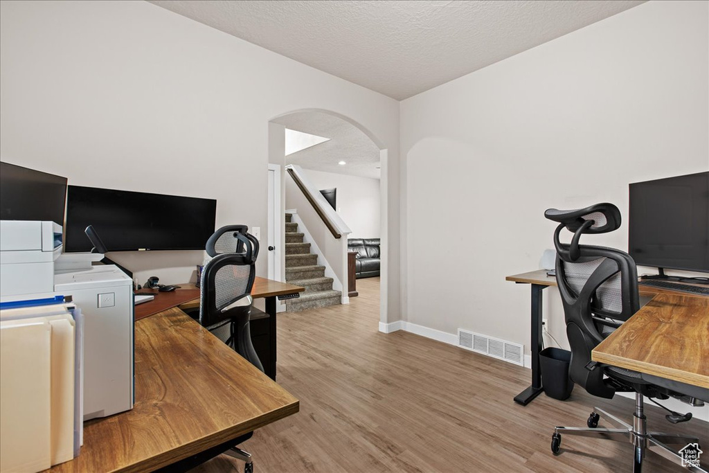 Office area with a textured ceiling and light wood-type flooring