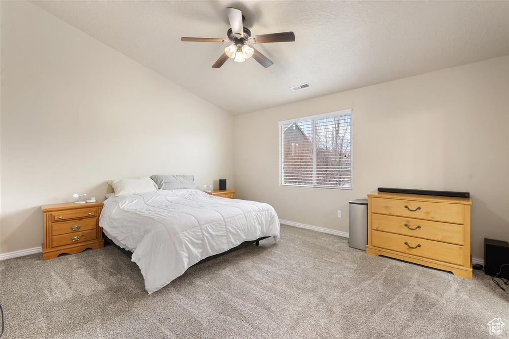 Carpeted bedroom with lofted ceiling and ceiling fan