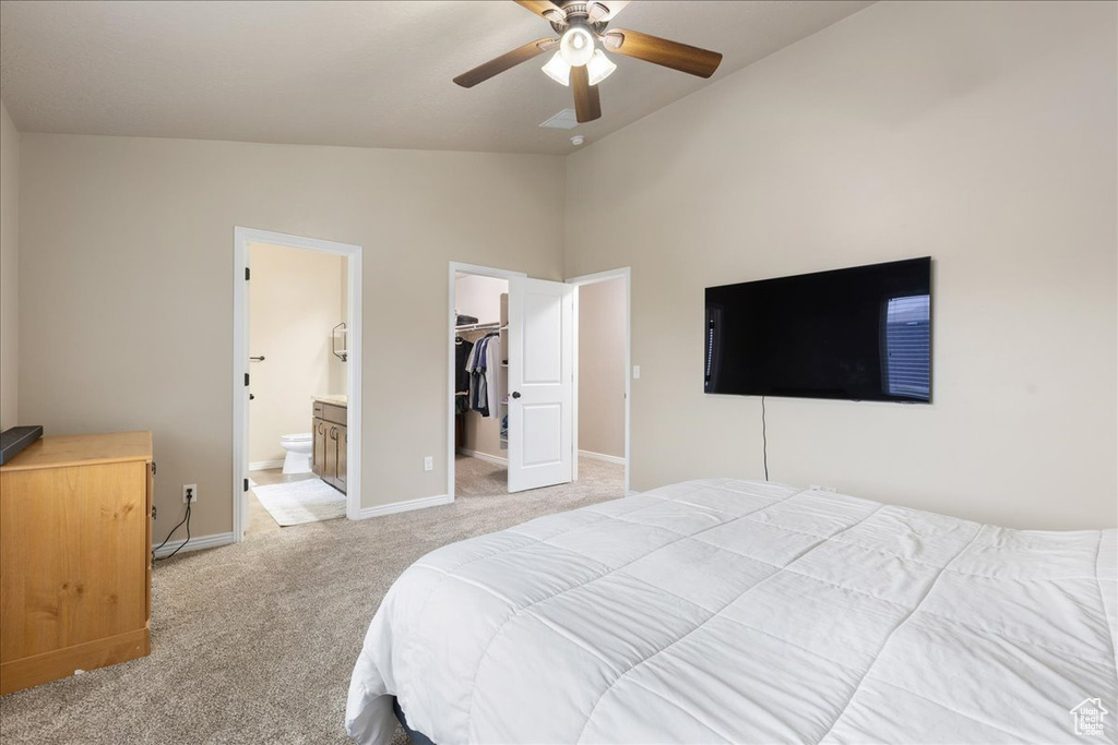 Carpeted bedroom featuring ensuite bath, ceiling fan, vaulted ceiling, a walk in closet, and a closet